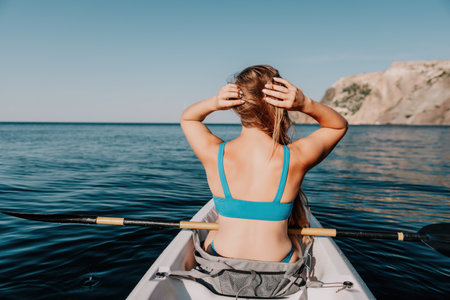 Woman in kayak back view. Happy young woman with long hair floating in kayak on calm sea. Summer...