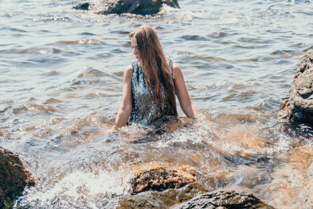 Woman summer travel sea. Happy tourist enjoy taking picture outdoors for memories. Woman traveler posing on the beach at sea surrounded by volcanic mountains, sharing travel adventure journeyの写真素材