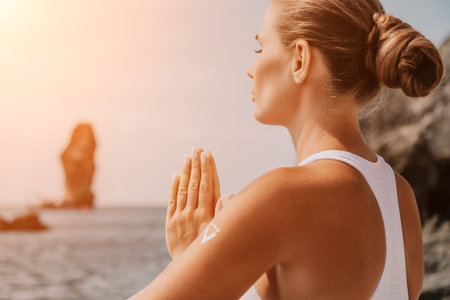 Woman sea yoga. Happy women meditating in yoga pose on the beach, ocean and rock mountains. Motivation and inspirational fit and exercising. Healthy lifestyle outdoors in nature, fitness concept.の写真素材