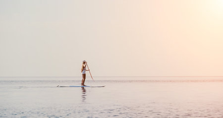 Woman sea sup. Close up portrait of happy young caucasian woman with long hair looking at camera and smiling. Cute woman portrait in bikini posing on sup board in the seaの写真素材