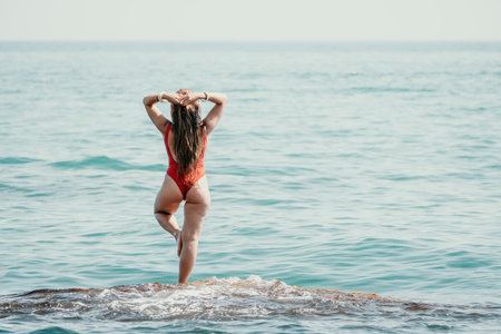 Woman sea yoga. Back view of free calm happy satisfied woman with long hair standing on top rock with yoga position against of sky by the sea. Healthy lifestyle outdoors in nature, fitness conceptの写真素材