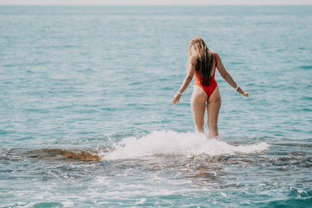 Woman sea yoga. Back view of free calm happy satisfied woman with long hair standing on top rock...