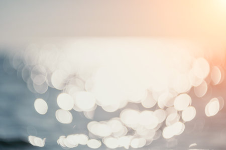Abstract sea summer ocean sunset nature background. Small waves on golden water surface in motion blur with golden bokeh lights from sun. Holiday, vacation and recreational concept.の写真素材
