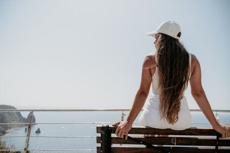 Woman summer travel sea. Happy tourist enjoy taking picture outdoors for memories. Woman traveler posing over sea bay surrounded by volcanic mountains, sharing travel adventure journeyの写真素材