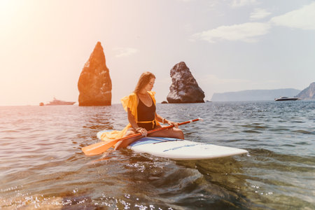 Woman sea sup. Close up portrait of happy young caucasian woman with long hair looking at camera and smiling. Cute woman portrait in bikini posing on sup board in the seaの写真素材