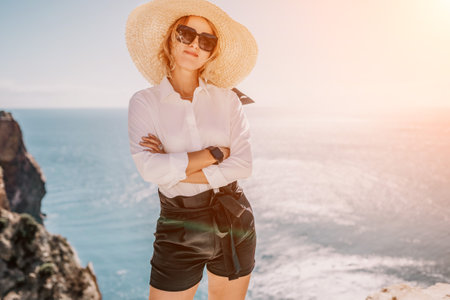 Woman sea hat. Business woman in yellow hat freelancer working over blue sea beach. Girl relieves stress from work. Freelance, digital nomad, travel and holidays conceptの写真素材