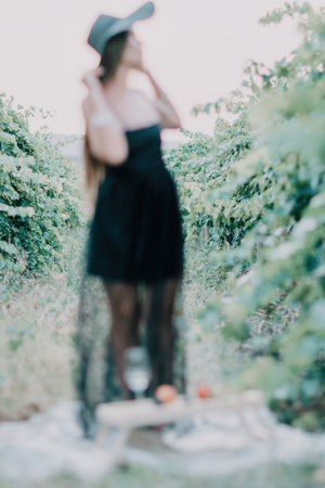 Woman travel winery. Portrait of happy woman holding glass of wine and enjoying in vineyard. Elegant young lady in hat toasting with wineglass smiling cheerfully enjoying her stay at vineyard.の写真素材