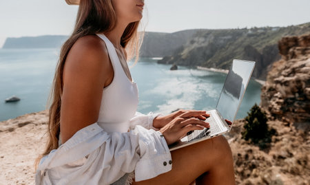 Woman sea laptop. Business woman in yellow hat freelancer with laptop working over blue sea beach. Girl relieves stress from work. Freelance, digital nomad, travel and holidays conceptの写真素材