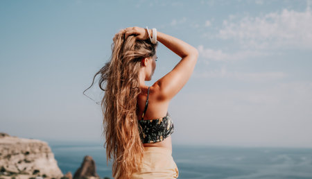 Woman travel sea. Happy tourist taking picture outdoors for memories. Woman traveler looks at the edge of the cliff on the sea bay of mountains, sharing travel adventure journeyの写真素材