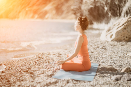Woman sea yoga. Selective focus. Young beautiful caucasian woman in a red suit practicing yoga on the beach at sunrise near the sea. Yoga. Healthy lifestyle. Meditation concept.の写真素材