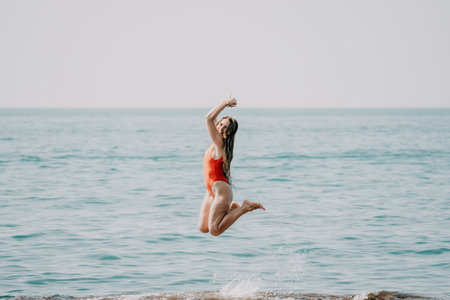 Woman sea yoga. Back view of free calm happy satisfied woman with long hair standing on top rock with yoga position against of sky by the sea. Healthy lifestyle outdoors in nature, fitness conceptの写真素材