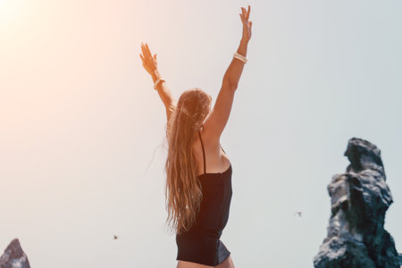 Woman summer travel sea. Happy tourist in hat enjoy taking picture outdoors for memories. Woman traveler posing on the beach at sea surrounded by volcanic mountains, sharing travel adventure journeyの写真素材