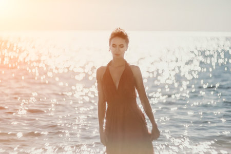 Woman in red dress on sea. Side view a Young beautiful sensual woman in a red long dress posing on the beach near sea on sunset. Girl on the nature on blue sky background. Fashion photo.の写真素材