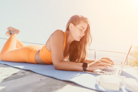 Woman laptop sea. Working remotely on seashore. Happy successful woman female freelancer working on laptop by the sea at sunset, makes a business transaction online. Freelance, remote work on vacationの写真素材
