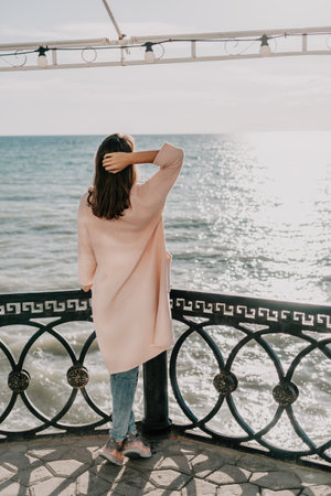 Woman summer travel sea. Happy tourist enjoy taking picture outdoors for memories. Carefree woman traveler posing on beach at sea on sunset, sharing travel adventure journey. Holiday vacation concept.の写真素材