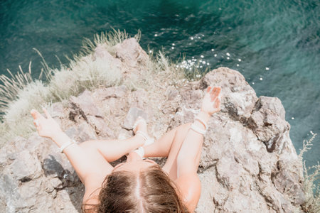 Woman sea yoga. Back view of free calm bliss satisfied woman with long hair standing on top rock with yoga position against of sky by the sea. Healthy lifestyle outdoors in nature, fitness concept.の写真素材