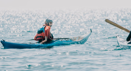 Man woman sea kayak. Happy free man and woman in kayak on ocean, paddling with wooden oar. Calm sea water and horizon in background. Active lifestyle at sea. Summer vacation.の写真素材