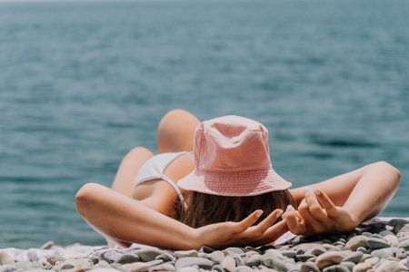 Unrecognizable positive woman in white bikini sunbathing or tanning on seaside beach during summer. happy tourist enjoying sun tan lying on beach chair lounge at luxury resortの写真素材