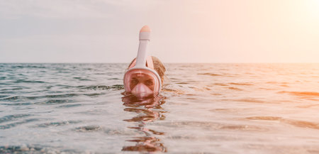 Young happy woman in white bikini and wearing pink mask gets ready for sea snorkeling. Positive smiling woman relaxing and enjoying water activities with family summer travel holidays vacation on sea.の写真素材