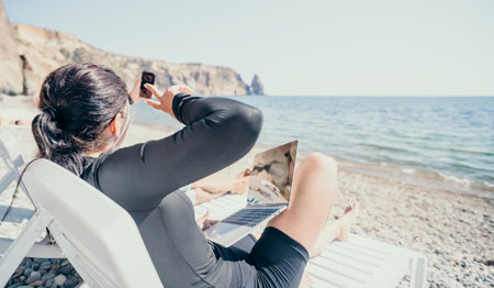 woman laptop sea. Working remotely on seashore. Happy successful lady, freelancer working on sea beach, relieves stress from work to restore life balance. Freelance, remote work on vacationの写真素材