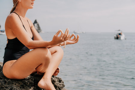 Woman sea yoga. Happy women meditating in yoga pose on the beach, ocean and rock mountains. Motivation and inspirational fit and exercising. Healthy lifestyle outdoors in nature, fitness concept.の写真素材