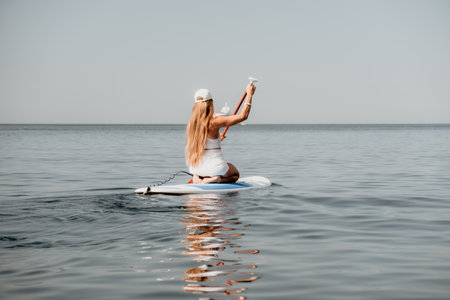 Woman sea sup. Close up portrait of happy young caucasian woman with long hair looking at camera and smiling. Cute woman portrait in bikini posing on sup board in the seaの写真素材