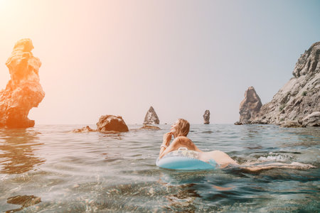 Woman summer sea. Happy woman swimming with inflatable donut on the beach in summer sunny day, surrounded by volcanic mountains. Summer vacation concept.の写真素材