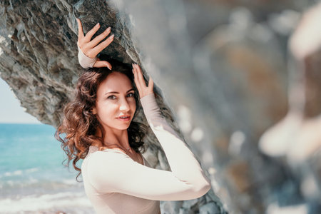 Woman travel sea. Sporty happy middle aged posing on a beach near the sea on background of volcanic...