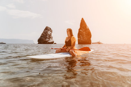Woman sea sup. Close up portrait of happy young caucasian woman with long hair looking at camera and smiling. Cute woman portrait in bikini posing on sup board in the seaの写真素材