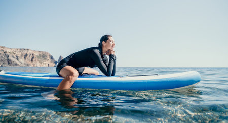 Woman sup yoga. Happy sporty woman practising yoga pilates on paddle sup surfboard. Female...