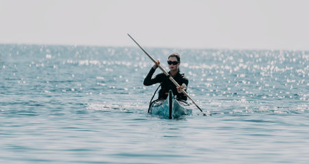 Woman sea kayak. Happy smiling woman in kayak on ocean, paddling with wooden oar. Calm sea water and horizon in background. Active lifestyle at sea. Summer vacation.の写真素材