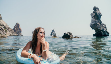 Woman summer sea. Happy woman swimming with inflatable donut on the beach in summer sunny day,...