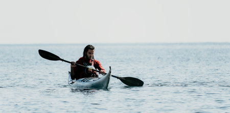 Man sea kayak. Happy free man in kayak on ocean, paddling with carbon paddle. Calm sea water and...