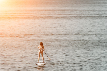 Sea woman sup. Silhouette of happy positive young woman in bikini, surfing on SUP board, confident...