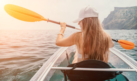 Woman in kayak back view. Happy young woman with long hair floating in transparent kayak on the...