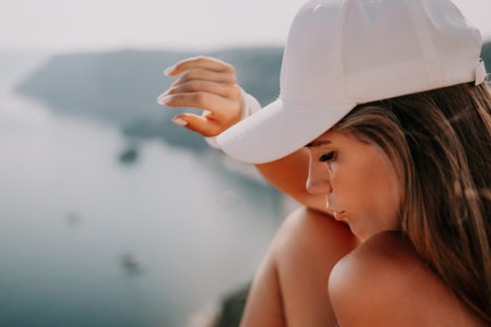 Woman travel sea. Happy tourist enjoy taking picture outdoors for memories. Woman traveler looks at the edge of the cliff on the sea bay of mountains, sharing travel adventure journeyの写真素材