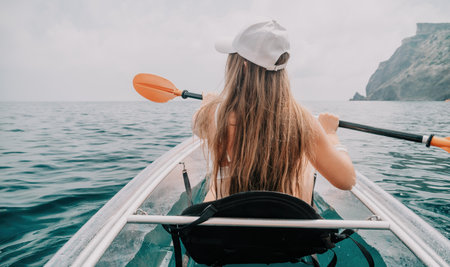 Woman in kayak back view. Happy young woman with long hair floating in transparent kayak on the...