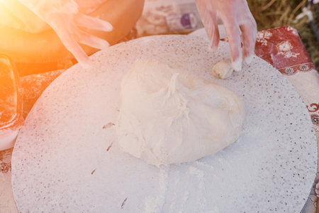 womans hands making qutab or chebureki with a rolling pin and minced meat onion in dough for...