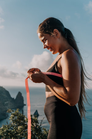 A woman is holding a pink tape measure and is measuring her breasts after morning fitness