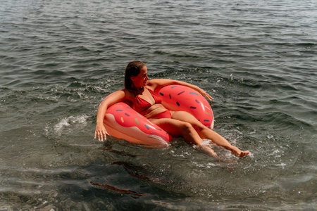 Summer Vacation Woman floats on an inflatable donut mattress, a water toy swim ring. Positive happy woman relaxing and enjoying family summer travel holidays vacation on the sea. Slow motionの写真素材