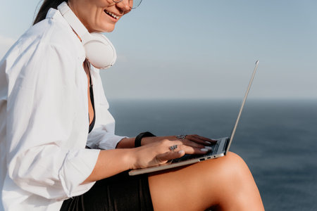 Woman sea laptop. Business woman, freelancer with laptop working over blue sea beach. Happy smiling girl relieves stress from work. Freelance, remote work on vacation, digital nomad, travel conceptの写真素材