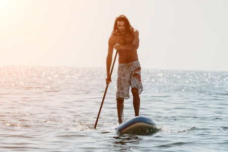 Man Sup Sea. Strong athletic man learns to paddle sup standing on board in open sea ocean on sunny...