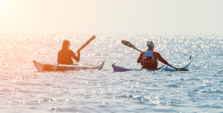 Man woman sea kayak. Happy free man and woman in kayak on ocean, paddling with wooden oar. Calm sea water and horizon in background. Active lifestyle at sea. Summer vacation.の写真素材