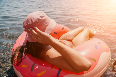 Summer Vacation Woman floats on an inflatable donut mattress, a water toy swim ring. Positive happy...