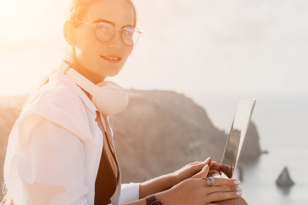 Woman sea laptop. Business woman, freelancer with laptop working over blue sea beach. Happy smiling girl relieves stress from work. Freelance, remote work on vacation, digital nomad, travel conceptの写真素材