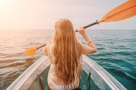 Woman in kayak back view. Happy young woman with long hair floating in transparent kayak on the...