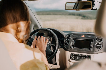 Happy woman talking on the phone while sitting in the car on nature Relaxed video call, professional...
