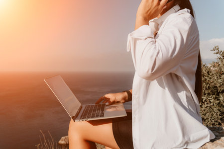 Woman sea laptop. Business woman, freelancer with laptop working over blue sea beach. Happy smiling girl relieves stress from work. Freelance, remote work on vacation, digital nomad, travel conceptの写真素材