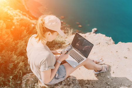 Woman sea laptop. Business woman, freelancer with laptop working over blue sea beach. Happy smiling girl relieves stress from work. Freelance, remote work on vacation, digital nomad, travel conceptの写真素材