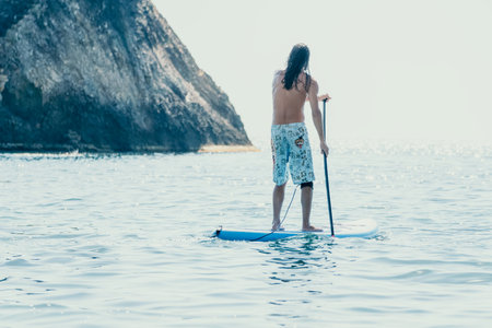 Man Sup Sea. Strong athletic man learns to paddle sup standing on board in open sea ocean on sunny...